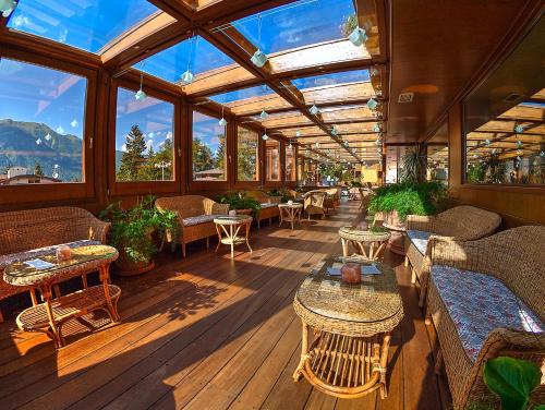 a large conservatory with tables and couches and windows at Luna Wellness Hotel in Folgarida