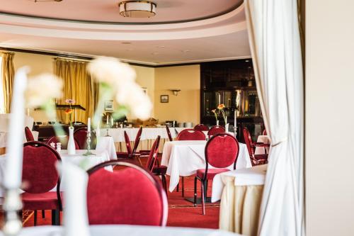 a restaurant with white tables and red chairs at Rheinhotel Schulz in Unkel