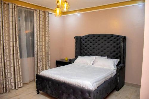 a bedroom with a bed with a black headboard at Secure cozy getaway near Kampala business district in Kampala