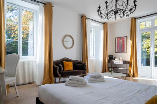 a bedroom with a bed and a chair and windows at Chateau des Ayes - Chambres & suites in Saint-Étienne-de-Saint-Geoirs