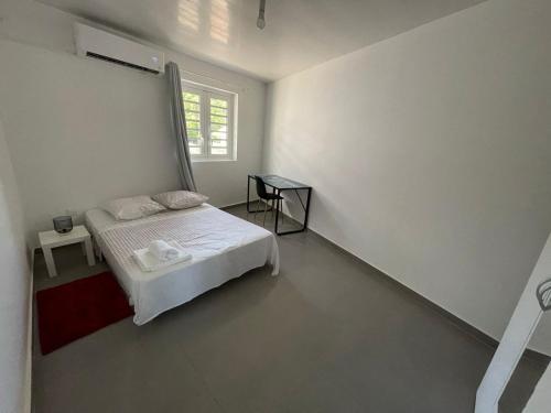 ein weißes Schlafzimmer mit einem Bett und einem Fenster in der Unterkunft Maison de Bourda in Cayenne