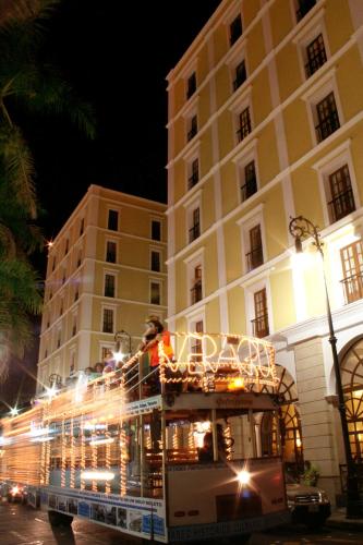 a double decker bus driving past a building at night at Gran Hotel Diligencias in Veracruz