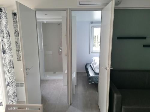 a hallway with a door to a room with a bed at Mobil Home 4-6 personnes in Gastes