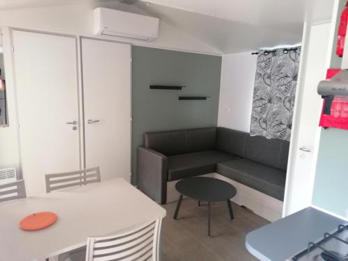 una pequeña sala de estar con sofá y mesa. en Mobil Home 4-6 personnes, en Gastes