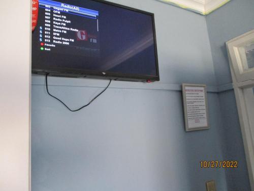 a flat screen tv hanging on a blue wall at PS GOOD TIME GUEST HOUSE in Klerksdorp