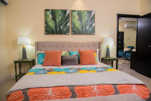 ein Schlafzimmer mit einem großen Bett mit orangefarbenen Kissen in der Unterkunft Hey Love in Ocho Rios