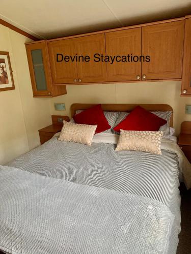 a bedroom with a bed with red and white pillows at Devine Staycations at 38 Riverside in Hawick