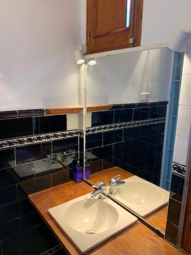 a bathroom with a sink and black tiles at Casa histórica Gines in Ginés