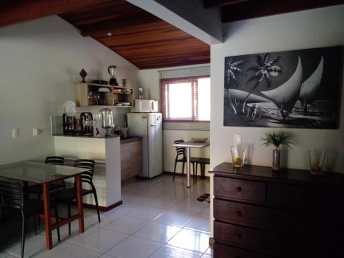 a kitchen and dining room with a table and a refrigerator at Sol da Pipa Flats Bosque da Praia in Pipa