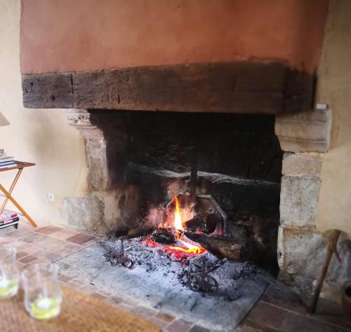 a brick fireplace with a fire in it at Chateau de Vaux in Gesnes-le-Gandelin