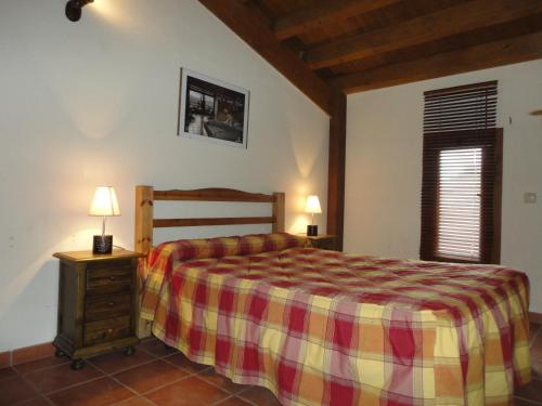 a bedroom with a bed with a plaid blanket and a window at Casas Rurales el Cerrete de Haro in Fuentelespino de Haro