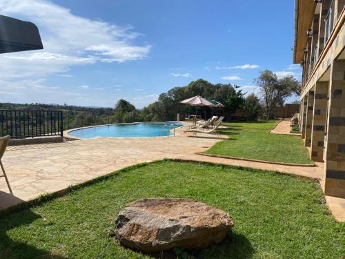 a large rock in the grass next to a swimming pool at Olesamara Collection in Nanyuki