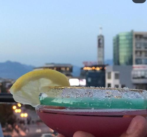 uma pessoa segurando uma bebida com uma fatia de limão em The Rooftop Hostel em Shkodër
