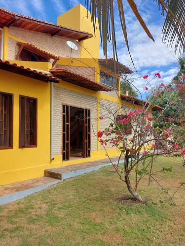 a yellow house with flowers in front of it at Quinta Zabelê in Barra Grande