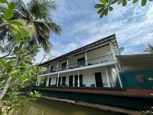 a house on the water with a palm tree at Villa Gaetano Unawatuna in Unawatuna