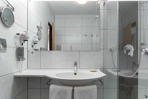 a white bathroom with a sink and a shower at Hotel Wolfringmühle in Fensterbach
