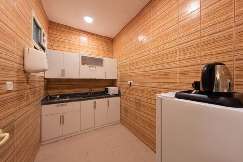 a kitchen with white cabinets and wooden walls at شقق قصر الممشى للوحدات السكنية in Jazan