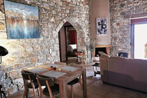sala de estar con mesa y pared de piedra en Villa Mavri Ruhige private Pool Villa, Meerblick, en Agia Paraskevi