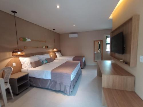 um quarto de hotel com duas camas e uma televisão de ecrã plano em Hotel Coco Beach em Conde