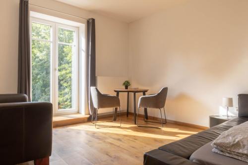 1 dormitorio con mesa, sillas y ventana en Designwohnung auf Gutshof mit Sauna zw. L/DD, en Mügeln