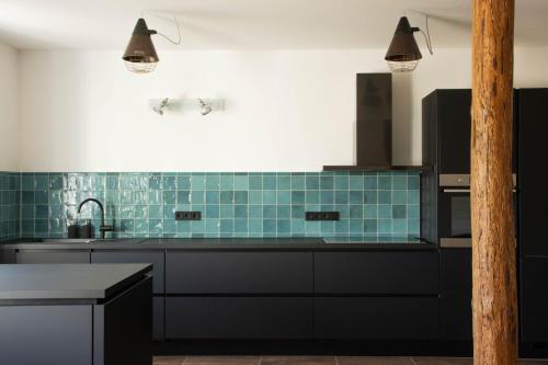 a kitchen with black cabinets and blue tiles at Designwohnung auf Gutshof mit Sauna zw. L/DD in Mügeln