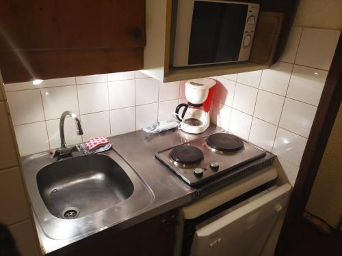 a kitchen counter with a sink and a stove at appartement au pied des pistes in Valmorel