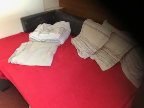 a red bed with two white sheets and pillows at appartement au pied des pistes in Valmorel