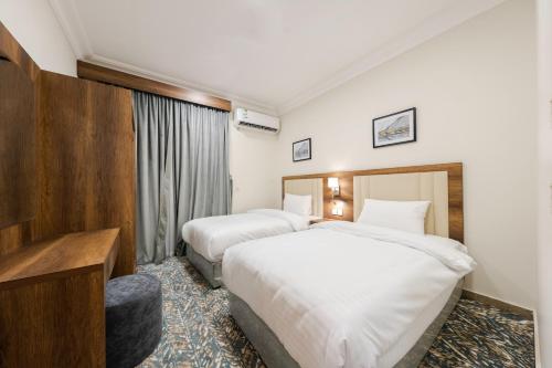 a hotel room with two beds and a television at شقق قصر الممشى للوحدات السكنية in Jazan