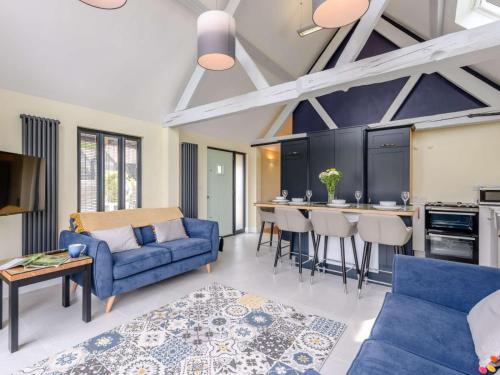a living room with a blue couch and a kitchen at dairy cottages in Wimborne Minster
