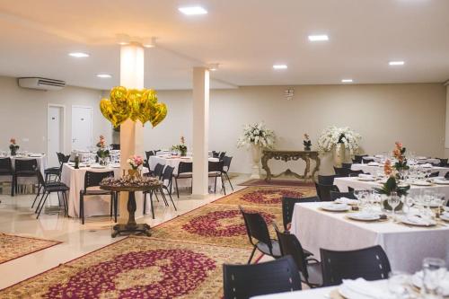 a banquet hall with white tables and black chairs at Goldmen Hotel in Cianorte