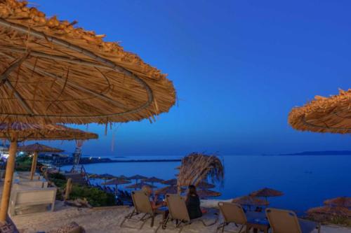 a group of chairs and umbrellas on a beach at G&L - Beautiful apartment just a few steps from the sea! in Kokkíni Khánion