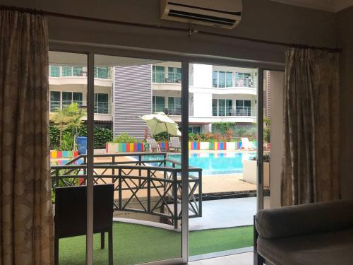 a balcony with a table with an umbrella and a pool at Perdana Serviced Apartment & Resorts in Kampung Padang Masirat