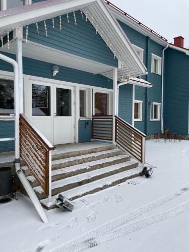 a blue house with a porch and stairs in the snow at Lapin Satu in Posio