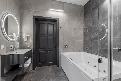 a bathroom with a tub and a sink and a mirror at Kievinn in Kyiv