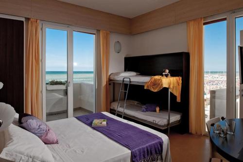 a bedroom with two beds and a balcony with the ocean at Hotel Universal in Senigallia