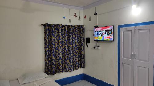 Cette chambre comprend un rideau et une télévision murale. dans l'établissement ADH Amilia Gardens, à Mysore