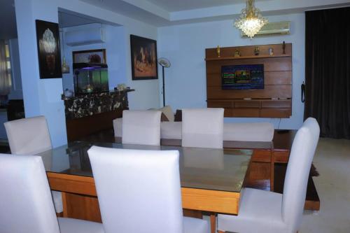 a dining room with a glass table and white chairs at Madinty Stay in Madinaty