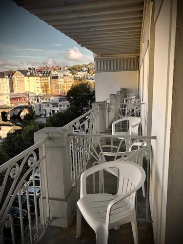 a balcony with white chairs and a view of a city at Grand Hôtel d'Espagne in Lourdes