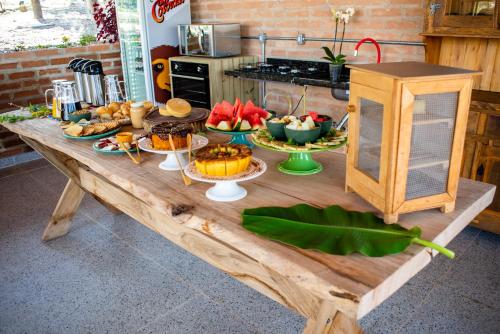 una mesa de madera con un montón de comida. en Casa Erva Doce Pousada, en Delfinópolis