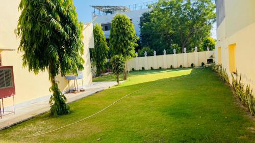 斋浦尔Saket Guest House Jaipur的带围栏的建筑物旁边的绿色草坪