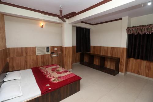 a bedroom with a bed with a red blanket on it at Jain Residency in Pachmarhī
