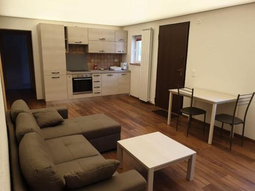 BnB Rivera-Monteceneri في ريفيرا: غرفة معيشة مع أريكة وطاولة ومطبخ