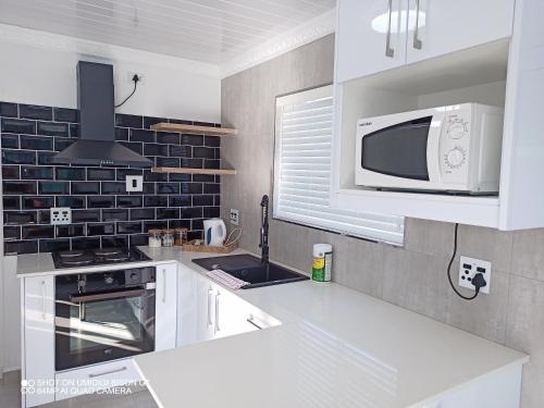 a kitchen with white cabinets and a microwave at Palm Tree in Cape Town