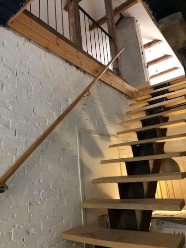 una escalera de madera en una habitación con una pared de ladrillo en Mysigt men trångt vindsrum i Svinaberga! en Kivik