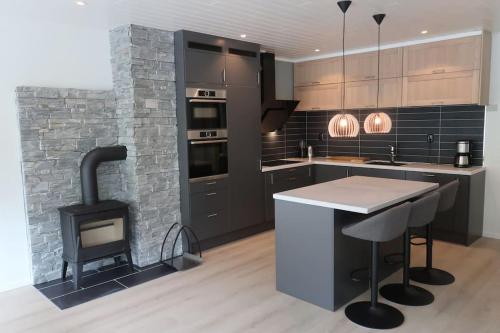 a kitchen with a stove and a stone wall at Moderne panoramaleilighet 3-roms i Olden in Olden