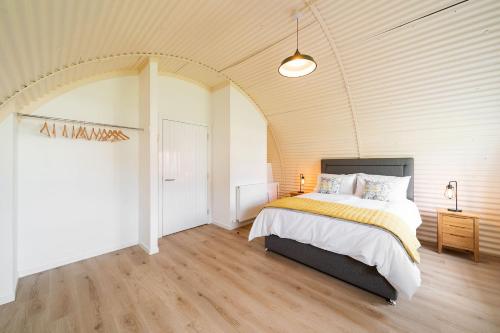 a bedroom with a bed and an arched ceiling at Cultybraggan Hut 34 in Mill of Fortune