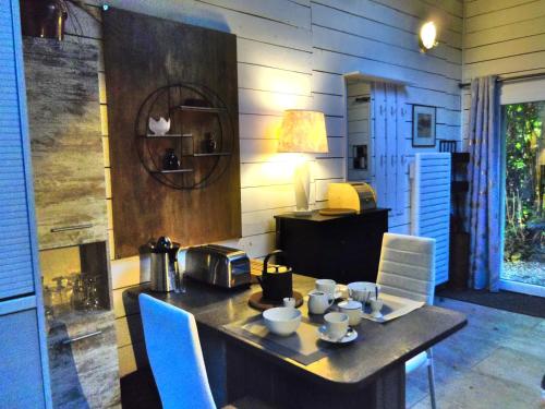 una mesa de comedor con sillas azules y una mesa con tazas y una lámpara. en À FLEUR D'EAU, en Sainte-Colombe-sur-lʼHers
