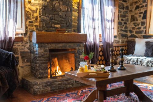 a living room with a stone fireplace and a table at 4 Seasons Premium Chalet in Palaios Agios Athanasios