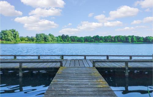 a wooden dock on a lake with trees in the background at Lovely Home In Heinkenszand With Sauna in Heinkensand