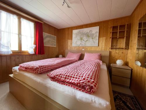 a bedroom with a bed with red and white comforter at Chalet Chutzli in Axalp